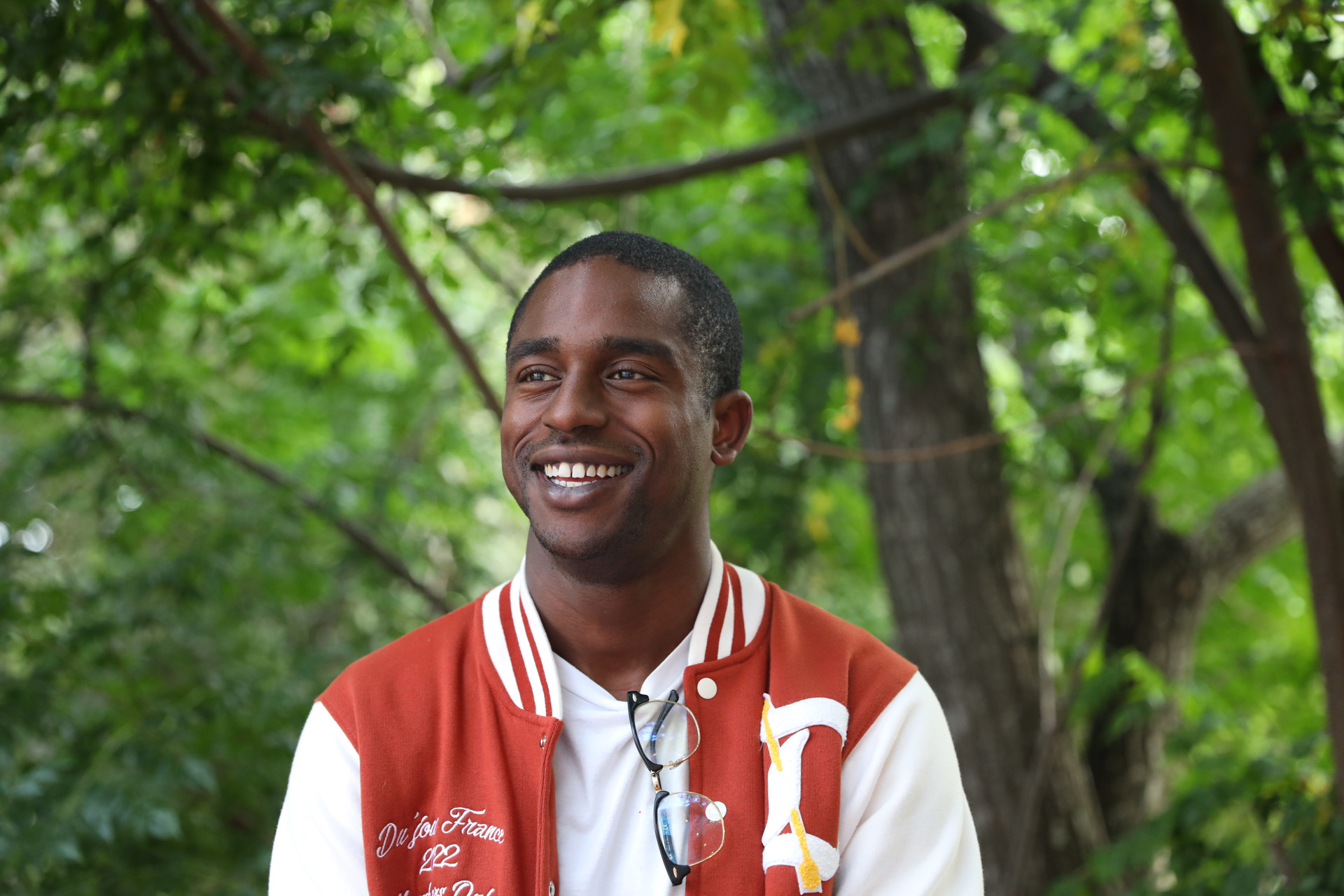 Justinn smiling outdoors among trees in a casual portrait for Pixel Pix Photos.
