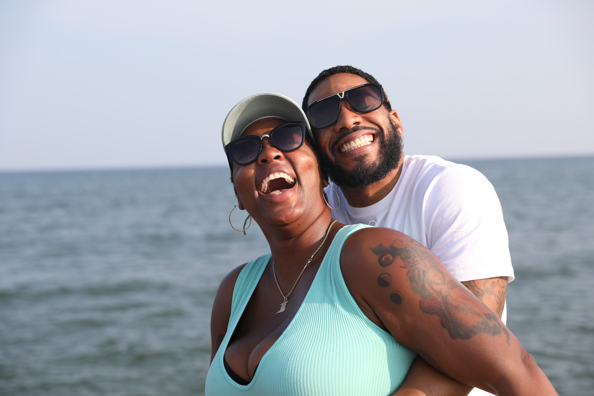 Couple portrait at the beach laughing together in soft evening light.